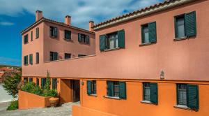 an orange building with green shutters on it at The Varos Residences Hotel in Város