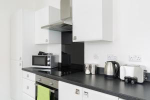 a kitchen with white cabinets and a black counter top at J Quarter - sleeps 5 long term & families comfortably, 4 beds, 2 bathrooms in Birmingham