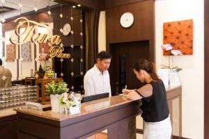 a man and a woman standing at a counter at Tara Place Hotel Bangkok in Bangkok