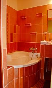 La salle de bains est pourvue d'une baignoire et de carrelage orange. dans l'établissement Panorama View Family Apartment, à Veszprém