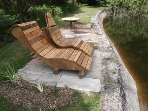 un banc en bois assis à côté d'un étang dans l'établissement le Crusoé à l'étang d'Anty - appartement, à Saint-Nabord