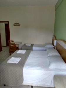 um quarto de hotel com três camas e uma mesa em Pousada Esquina do Sol em Rio Grande