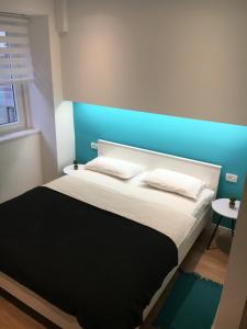a bedroom with a large bed with a blue headboard at Flumen in Rijeka