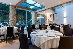 ein Restaurant mit weißen Tischen und Stühlen und großen Fenstern in der Unterkunft Ele Green Park Hotel Pamphili in Rom