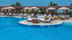 a swimming pool with chairs and umbrellas next to a swimming pool at Varos Village Boutique Hotel - Holistic Experience in Város
