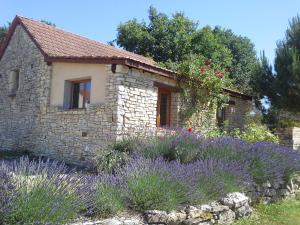 a stone house with purple flowers in front of it at Le Hameau des Cardenals in Salviac