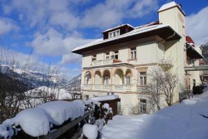 ein großes Haus mit Schnee auf dem Boden in der Unterkunft Villa Excelsior Hotel & Kurhaus in Bad Gastein