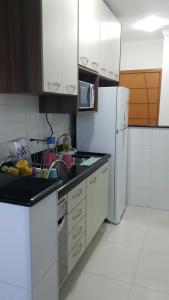 una cucina con armadietti bianchi e frigorifero bianco di APARTAMENTO - GUILHERMINA - PRAIA GRANDE a Praia Grande