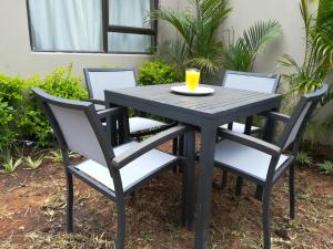 Angel Guest House في مابوتو: طاولة سوداء وكراسي مع كوب من عصير البرتقال