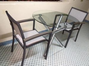 a glass table and a chair sitting next to a wall at Angel Guest House in Maputo