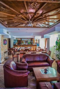 a living room with a leather couch and tables at Bariakov Family Hotel in Bansko