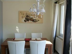 ハーグナウにあるFerienwohnung Bertaのダイニングルームテーブル(白い椅子付)、シャンデリア