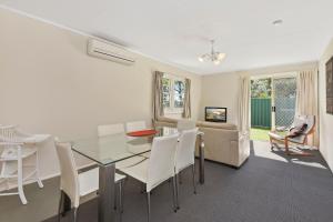 a dining room with a glass table and white chairs at Diamond Waters Caravan Park in Dunbogan