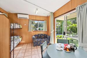 uma sala de estar com uma mesa e um quarto com uma cama em Diamond Waters Caravan Park em Dunbogan