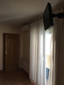 a room with a window with a television and a curtain at VILLA HISPANO-BRASILEÑA-Fiestas NO in Purchil