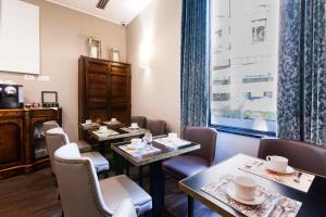 una sala da pranzo con tavoli, sedie e una finestra di Giuturna Boutique Hotel a Roma