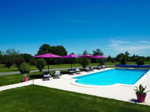 a swimming pool with chairs and purple umbrellas at Villas de Leypinas Gites in Saint-Pardoux-Corbier