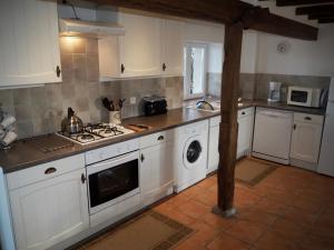 a kitchen with white cabinets and a stove top oven at Villas de Leypinas Gites in Saint-Pardoux-Corbier