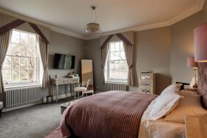 a bedroom with a bed and two windows and a desk at B&B Downham Hall in Wickford