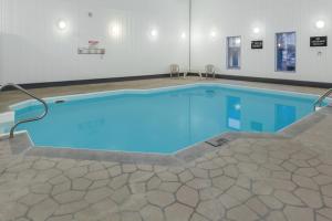 ein großer Pool mit blauem Wasser in einem Gebäude in der Unterkunft Super 8 by Wyndham Medicine Hat AB in Medicine Hat