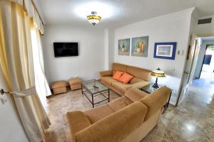 ein Wohnzimmer mit einem Sofa und einem Tisch in der Unterkunft Chalet El Naranjo in Sevilla