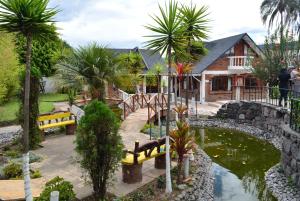 ein Haus mit einem Teich, Bänken und Palmen in der Unterkunft Hosteria Quinta Paraiso in Quito