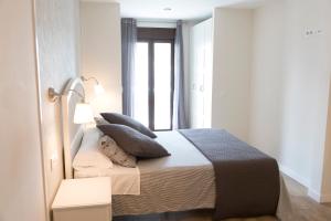a bedroom with a bed with pillows and a window at Apartamentos Sol Real in Úbeda