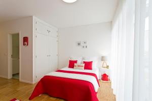 Dormitorio blanco con cama roja y blanca en Sereia Garden Apartment, en Coímbra