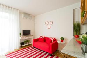 a living room with a red couch and a tv at Sereia Garden Apartment in Coimbra