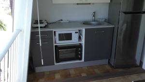 une petite cuisine avec un évier et un micro-ondes dans l'établissement Location Village Soleil Privative, au Gosier