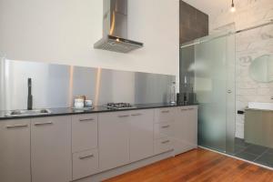 a kitchen with white cabinets and a glass shower at Indulge Apartments - The Urban Collection in Mildura +64 photos