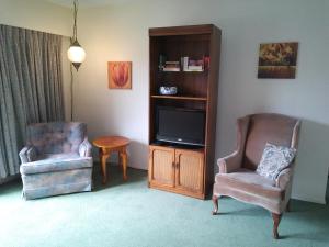 a living room with a tv and two chairs at Rosedale Manor in Duncan