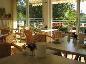 um restaurante com mesas e cadeiras de madeira e janelas em Hotel Haus Bismarck em Berlim