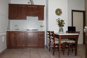 a kitchen with wooden cabinets and a table with chairs at Residence La Piscina in Isola del Gran Sasso dʼItalia