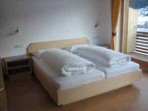 a bed with two pillows on it in a room at Garni - Appartement Neumairhof in Rasun di Sopra