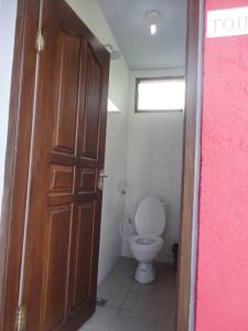 a bathroom with a toilet and a wooden door at Jazz Senggigi Hotel in Senggigi