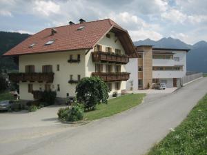 a house with a red roof on a road at Garni - Appartement Neumairhof in Rasun di Sopra