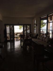 a living room with a couch and tables and windows at Sun N Sea Hotel in Unawatuna