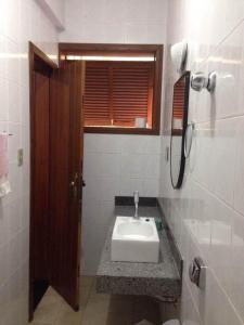 baño con lavabo blanco y ventana en Sefiroh Hostel en Viçosa