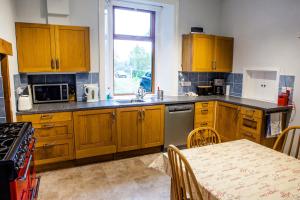cocina con armarios de madera, mesa y ventana en Shelburne Lodge en Cairnbaan