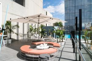 un patio al aire libre con mesas, sillas y una sombrilla en Adelphi Hotel, en Melbourne