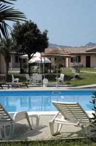 een zwembad met 2 ligstoelen naast een huis bij Hotel Giannina in Forlimpopoli