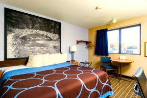 a hotel room with a bed and a desk and a window at Super 8 by Wyndham Burlington in Burlington