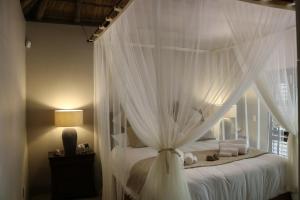 a bedroom with a canopy bed with white curtains at Luvivane Luxury Villa in Marloth Park