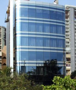 a blue glass building with trees in front of it at Svenska Design Hotel in Mumbai