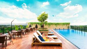 a woman sitting on a chair next to a swimming pool at Satoria Hotel Yogyakarta - CHSE Certified in Yogyakarta