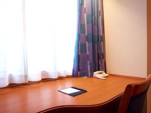 a wooden desk with a phone and a book on it at Hotel Roco Inn Okinawa in Naha