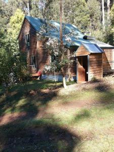 a wooden house with a gambrel roof on a yard at Lyrebird Gully Retreat in Hallston