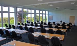 uma sala de aula com mesas e cadeiras numa sala com janelas em Wildpark Hotel em Bad Marienberg