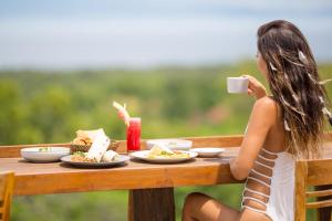 a woman sitting at a table with a cup of coffee at Semabu Hills Hotel Nusa Penida in Nusa Penida